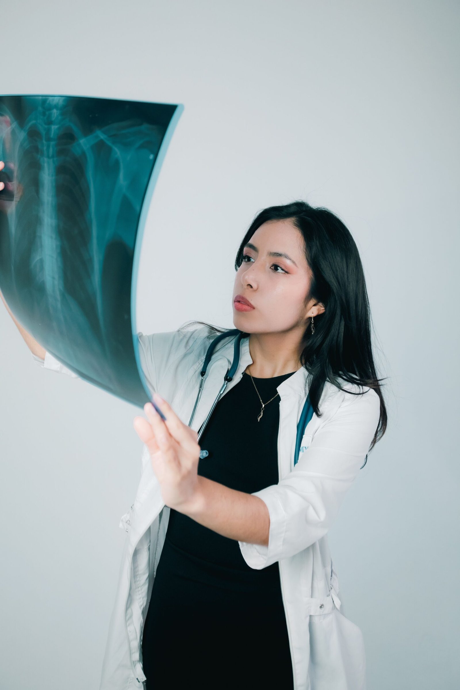 Female doctor examining a chest x-ray in a clinical setting, emphasizing medical professionalism.