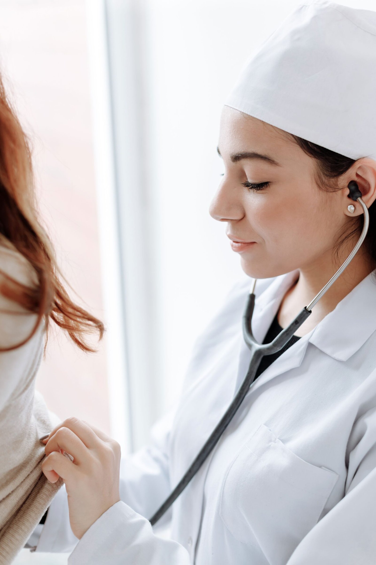 Female doctor using stethoscope during medical check-up, focusing on patient care.